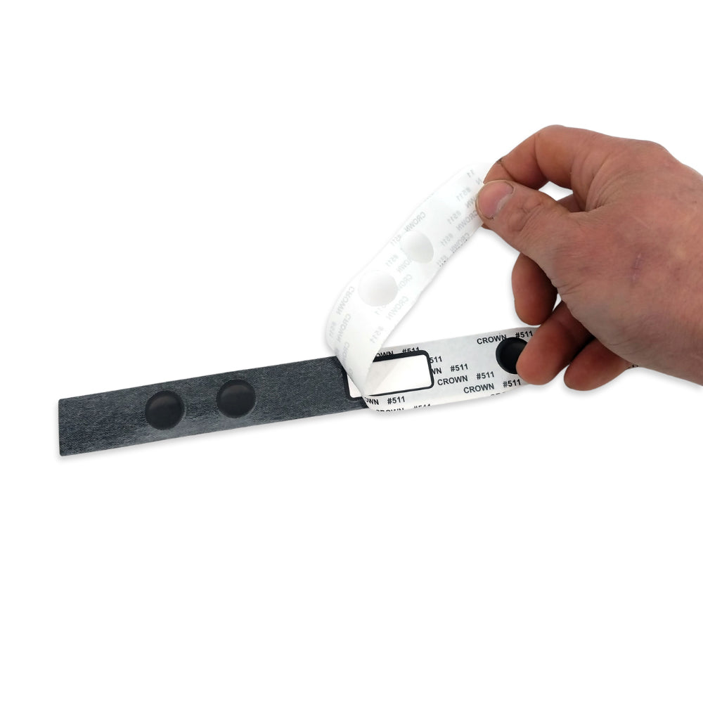 Hand holding a white plastic strip with measurement markings on a white background