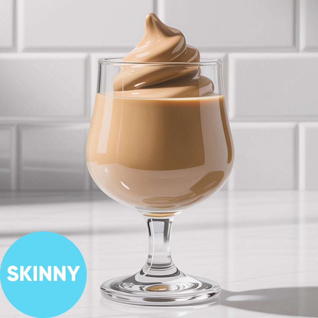 A clear stemmed glass filled with Frozen Skinny Hard Irish Cream VINKA Slushy Kit (2L), set on a white surface against a white subway-tile background. A bright blue circle in the lower left reads “SKINNY.