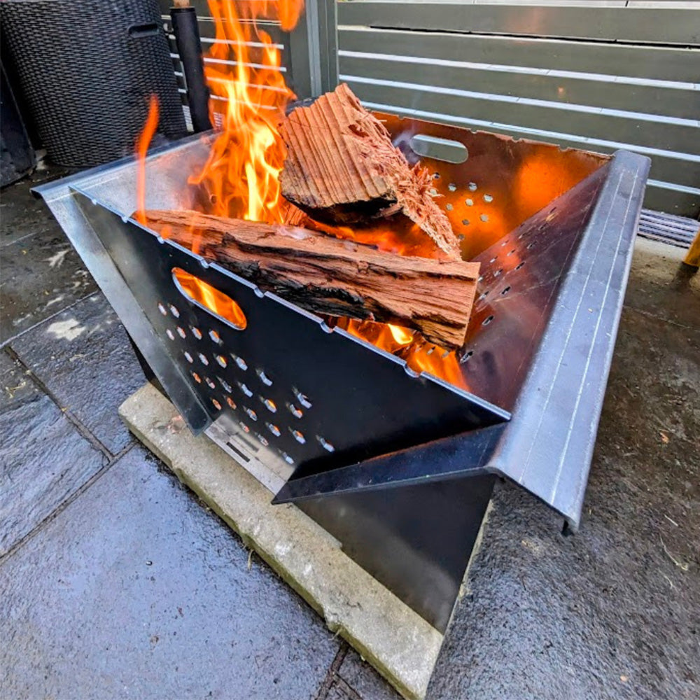 Metal fire pit with burning wood on a stone patio