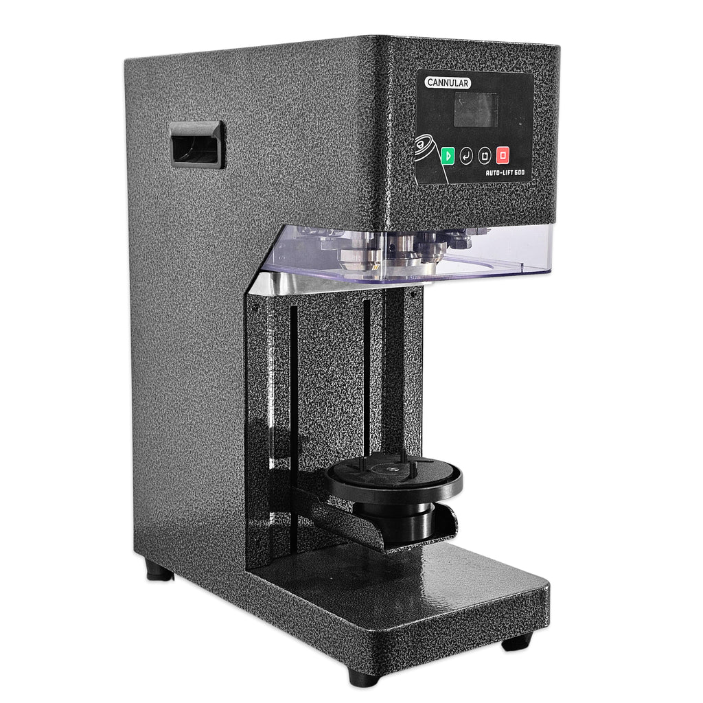 A black textured countertop machine with a digital control panel on top, a clear acrylic cover, and a circular press head over a flat base, shown on a plain white background.