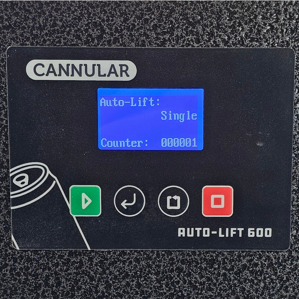 A close-up of a black industrial control panel labeled CANNULAR, with a blue LCD screen showing settings and four control buttons including green, white, white, and red icons. The panel is set against a textured gray background.